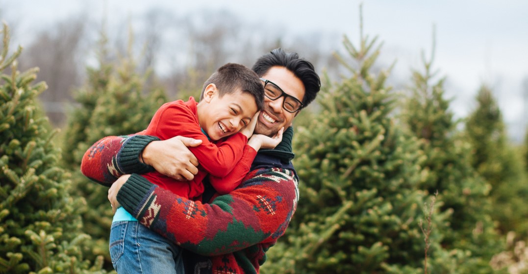 man and his child celebrating merry christmas with christmas trees