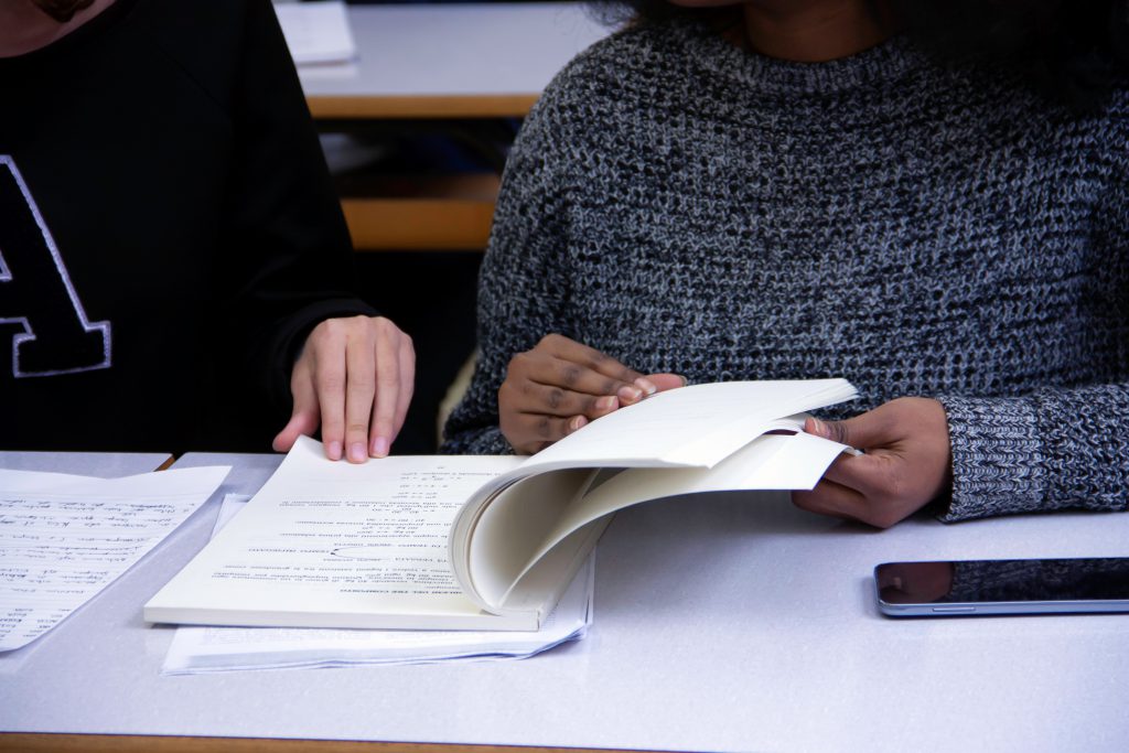 two friends studying together in class the differences in English and Geramn, flicking through notes