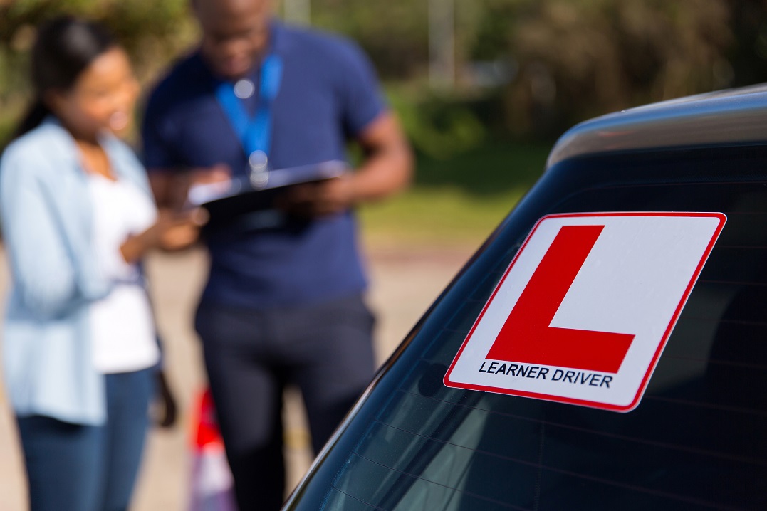 a girl getting feedback from her driving licence test in germany. Plus close up of the learner sticker.