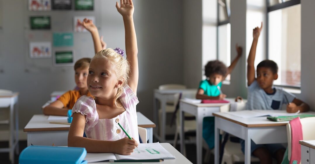 students in a german school raising hands in class