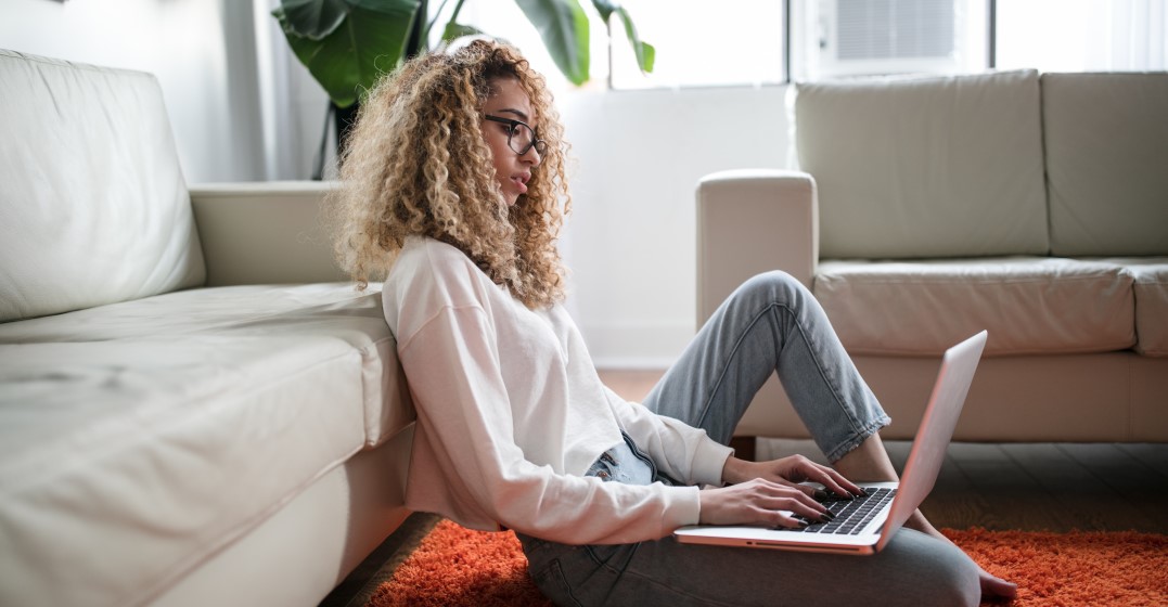 Eine Frau auf dem Boden sitzend mit ihrem Laptop macht den Lingoda Sprint