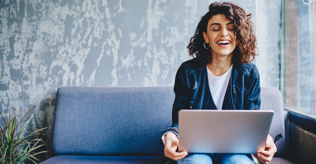 Woman sitting on a couch with a laptop thining about reasons to learn Spanish