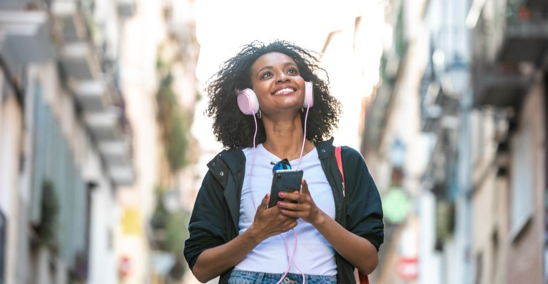 A young woman with headphones listening to happy expressions in French