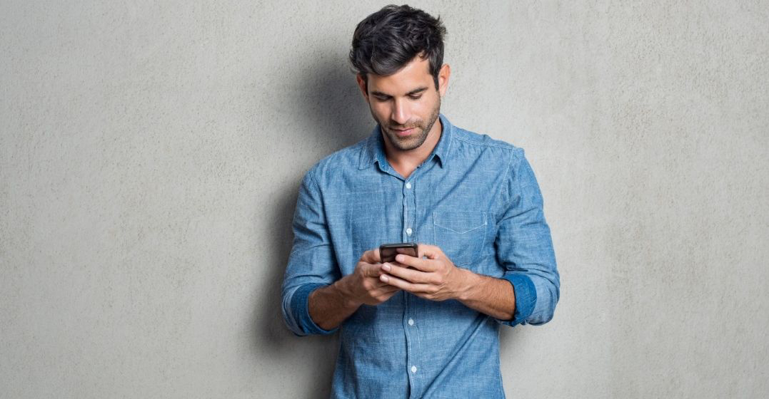 Ein Mann schaut auf seinem Smartphone nach, wie er sein Deutsch verbessern kann