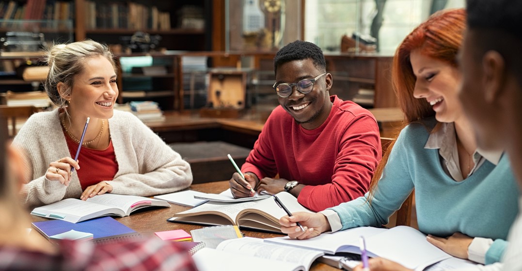 Students at a table with textbooks talking about the hardest languages to learn