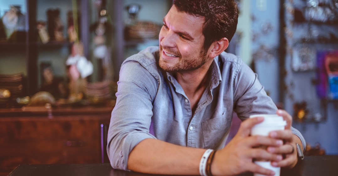 Lächelnder Mann mit einem Kaffee vergleicht Lingoda, Babbel und Duolingo