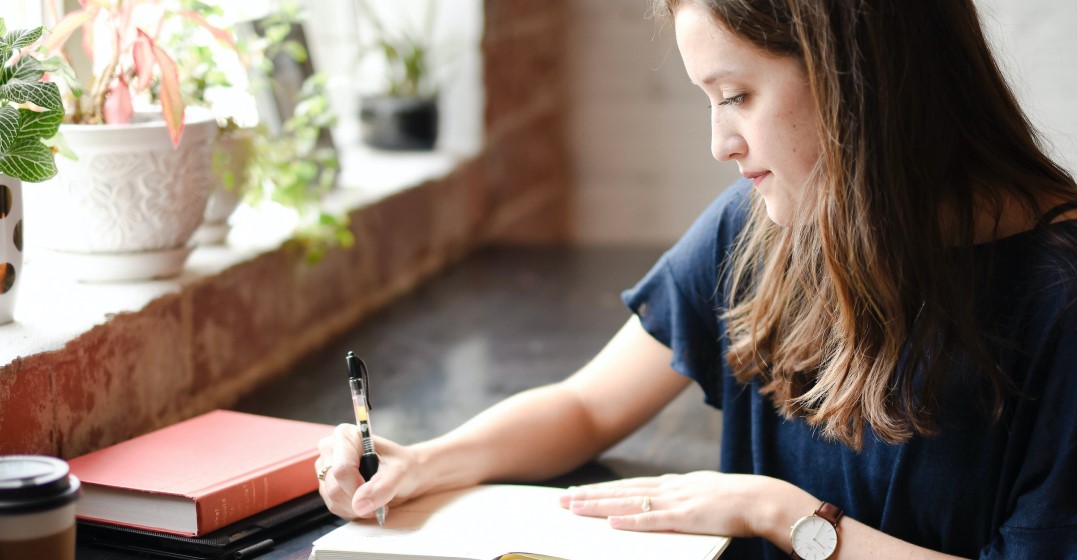 A young woman writing down notes about the German umlauts