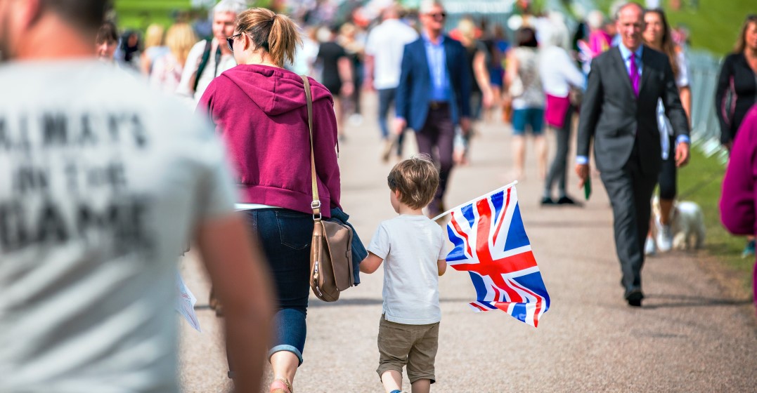 Woman with ther child holding a Birtish flag talking in a posh British accent