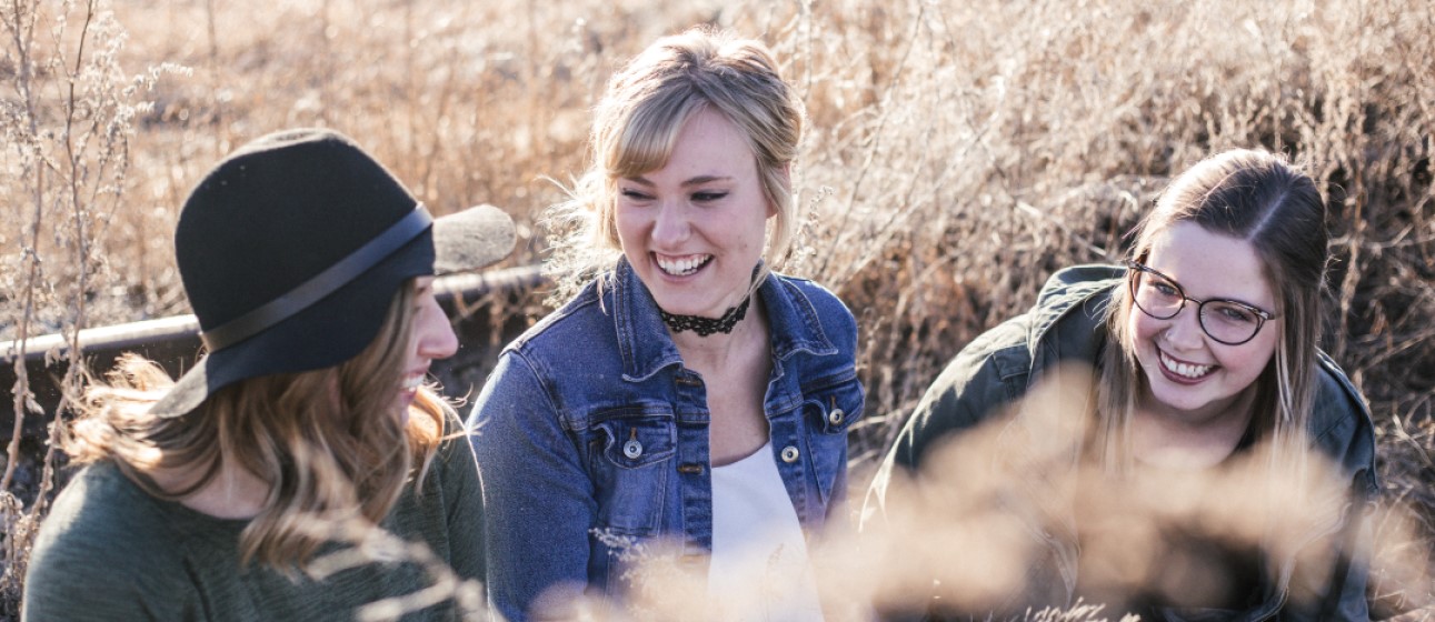 THree friends in a field talking about English tenses