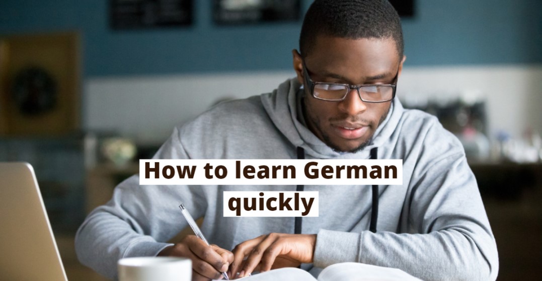 A young man writing into his notebook learning German in 3 months