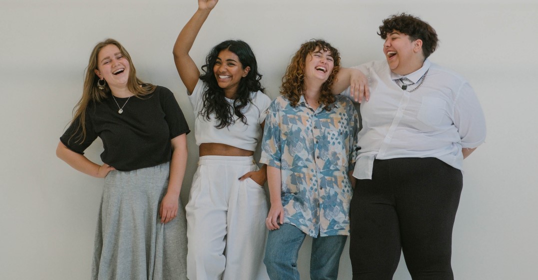 Four young people standing and laughing about German jokes