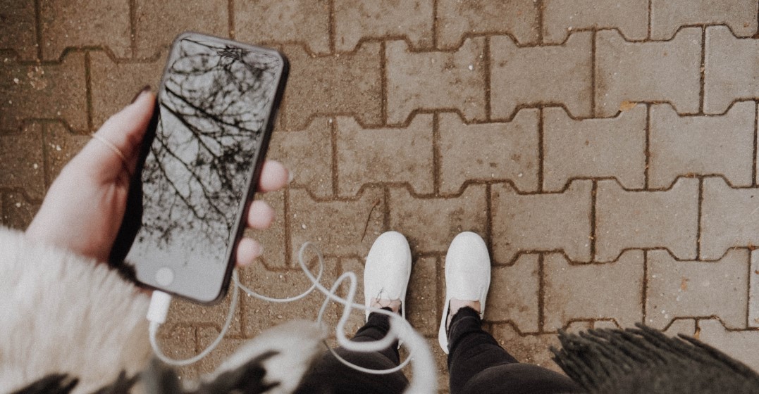 Eine Hand hält ein Smartphone mit englischen Podcasts