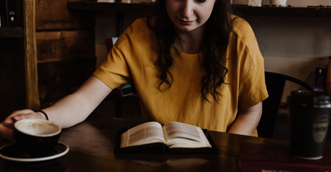 A young woman reading a book about what etymology is