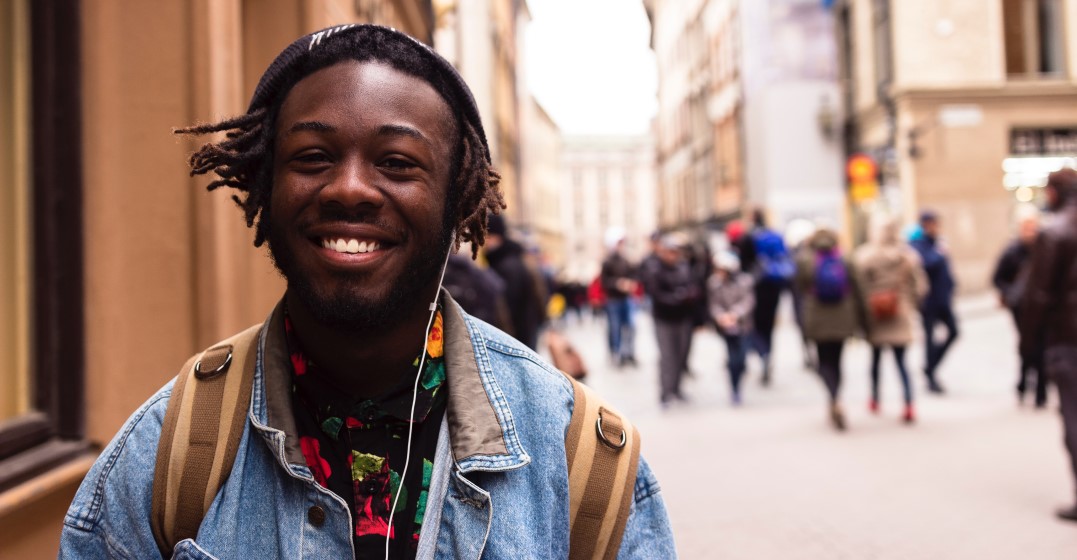 Young man smiling walking in a street learning ways to ask 