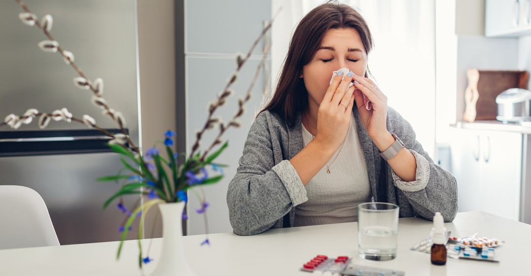 woman with allergies blowing her nose