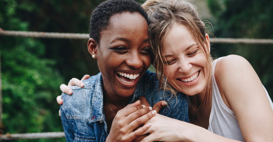 Two friends holding hands and laughin about French quotes about life