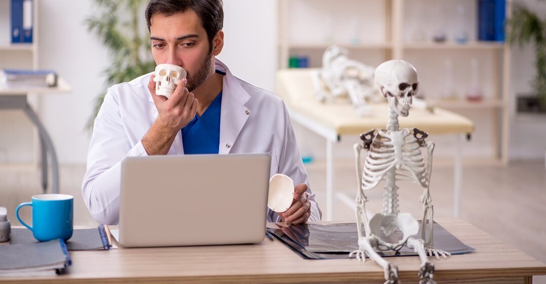 Young,Male,Doctor,Studying,Human,Skeleton,At,The,Hospital