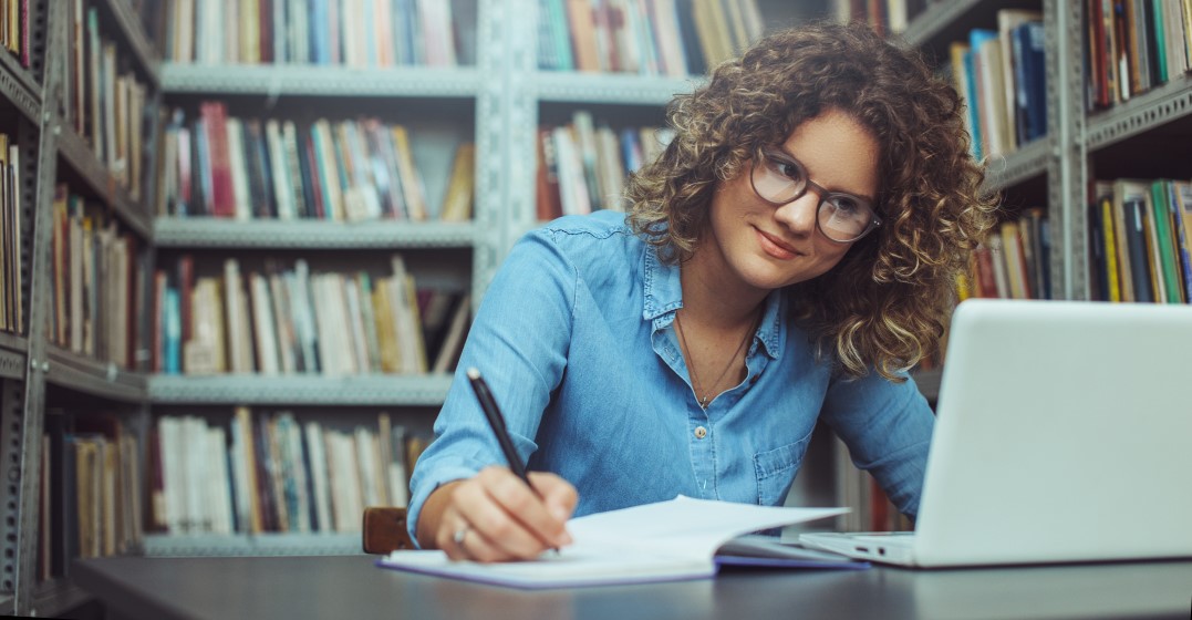A woman in a library looking up all about the verb to be in English