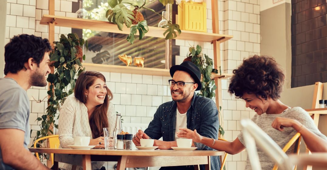 Four friends sitting at a table, laughing and chatting