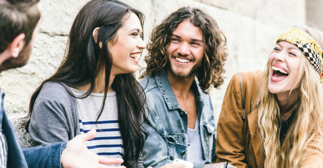 Four friends sitting next to eachother, tlaking and laughing