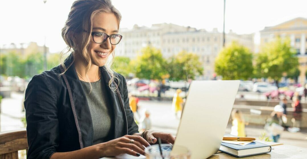 Smiling woman working on a laptop on a terrace