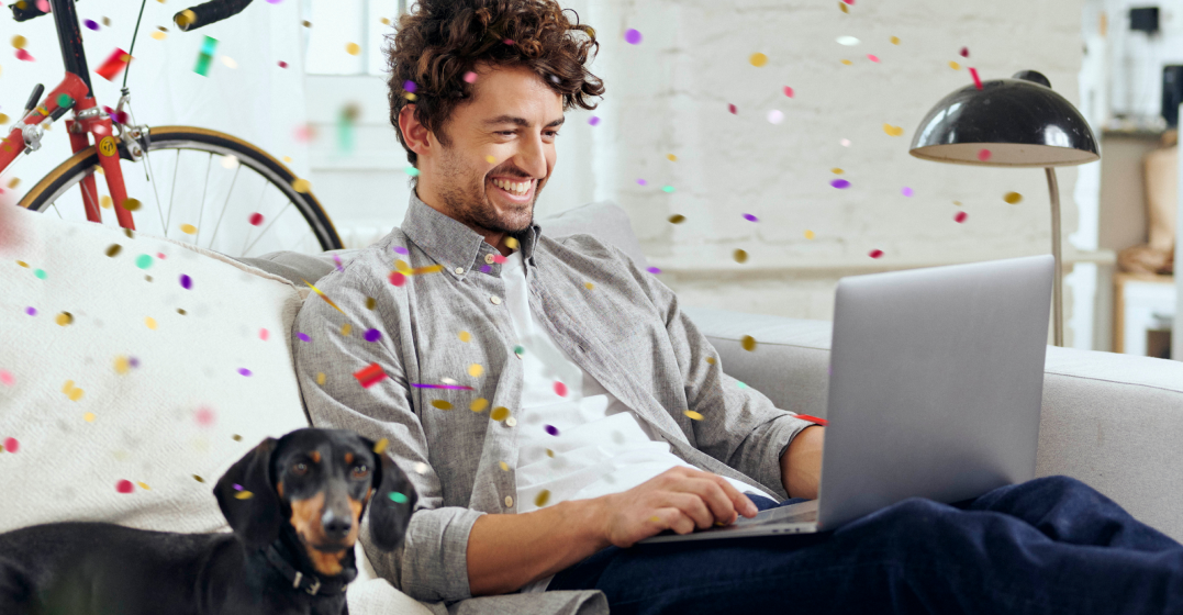 Mann sitzt auf einer Couch mit einem Laptop und recherchiert den Lingoda Mini-Sprint, KOnfetti im Hintergrund