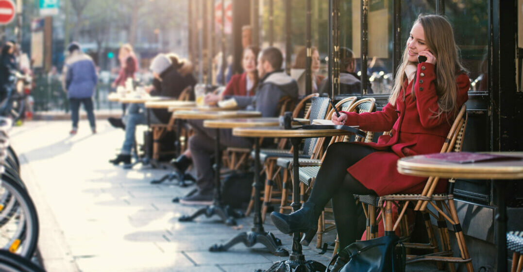Moving to France- young woman sitting in a street café