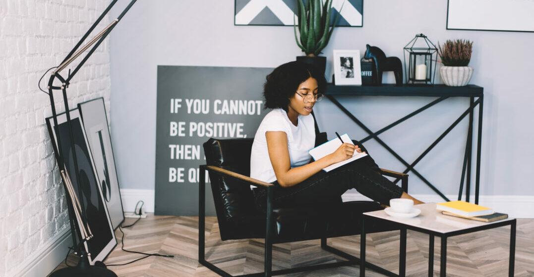 How to learn English writing - woman on a chair writing in a notebook