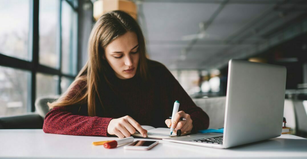 Girl taking notes in front of a laptop about French articles