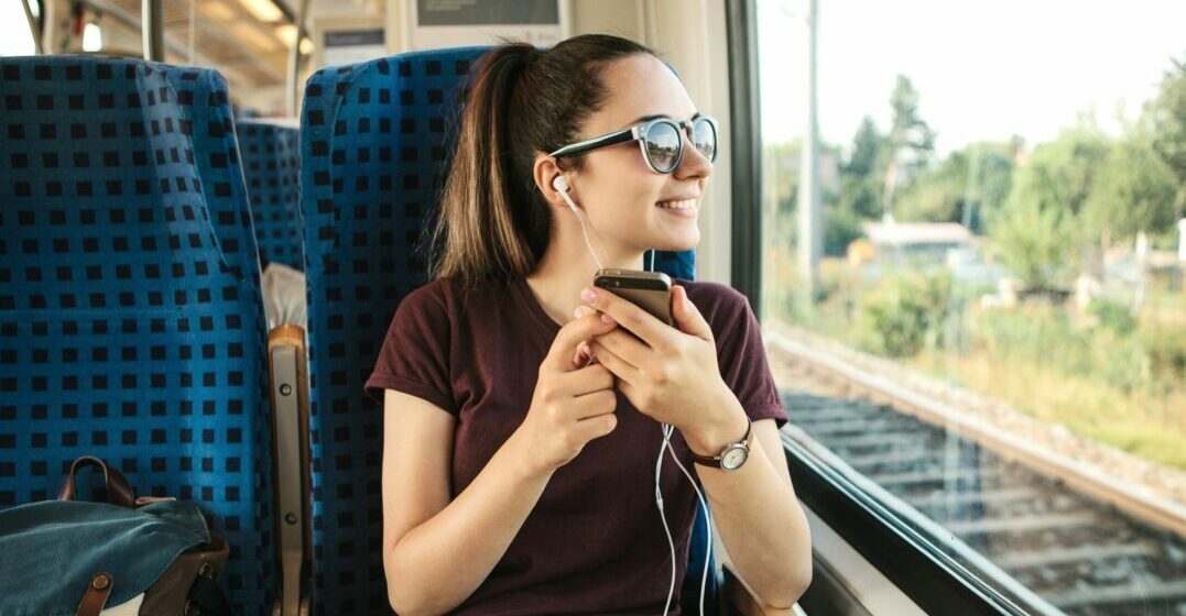 Una mujer en el tren escuchando un pódcast para aprender inglés