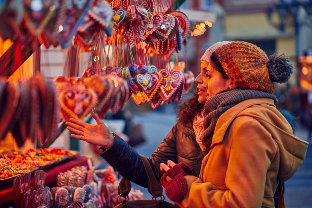 Amigos comprando dulces en el mercado navideño y hablando de tradiciones navideñas originales