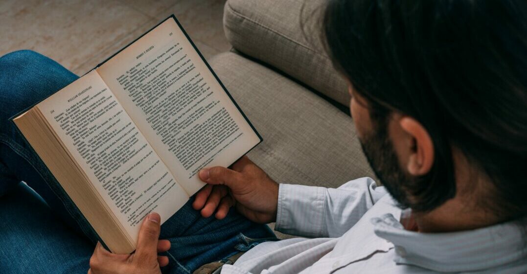 Ein Mann liest ein Buch in altenglischer Schrift über die Geschichte der englischen Sprache