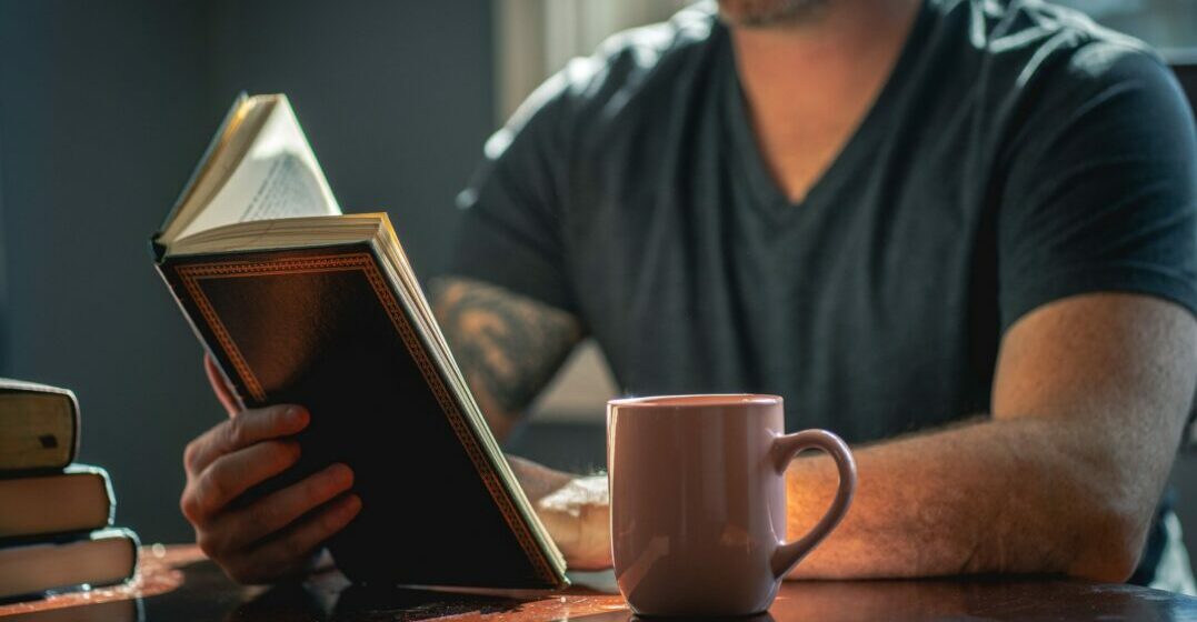 Man reading a book about German philosophers at a table