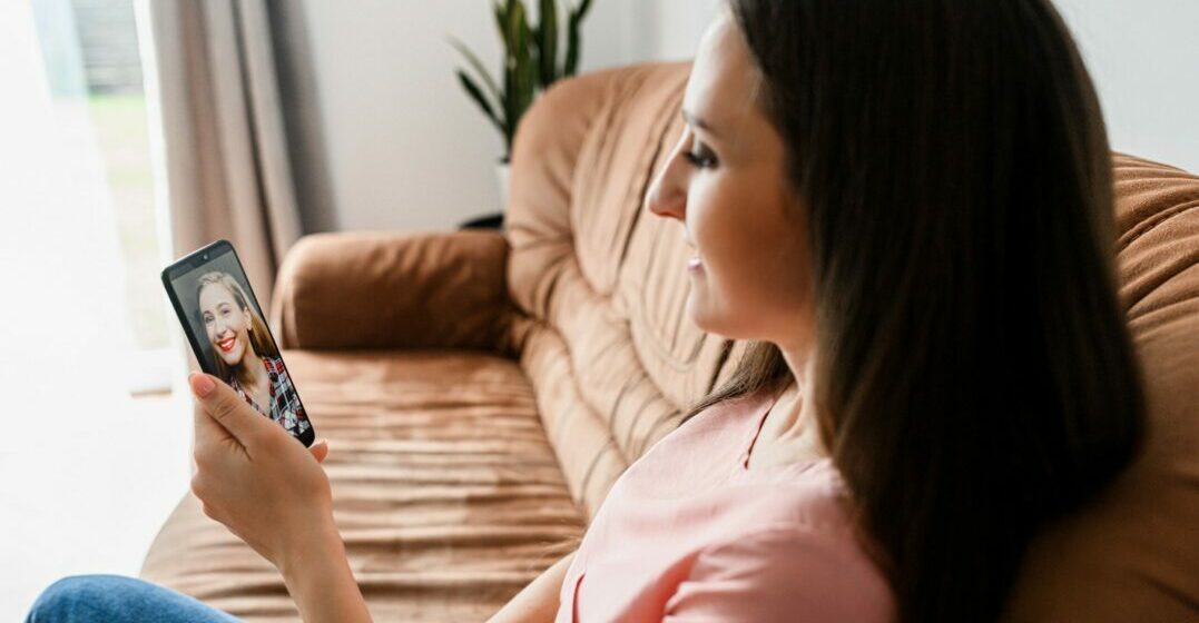 WOman sitting on a sofa with her phone doing a tandem language exchange