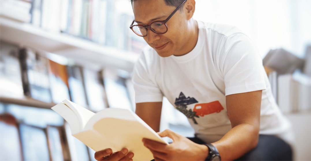 man reading up word origins on a dictionary