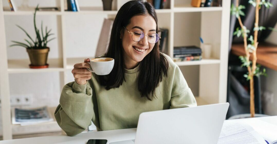 Young woman at her laptop smiling and studying the differences between you and you're