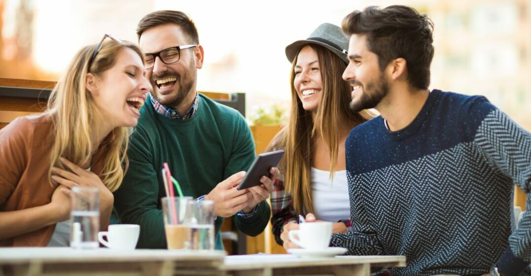 Four friends at a table laughing and speaking in a Geordie accent