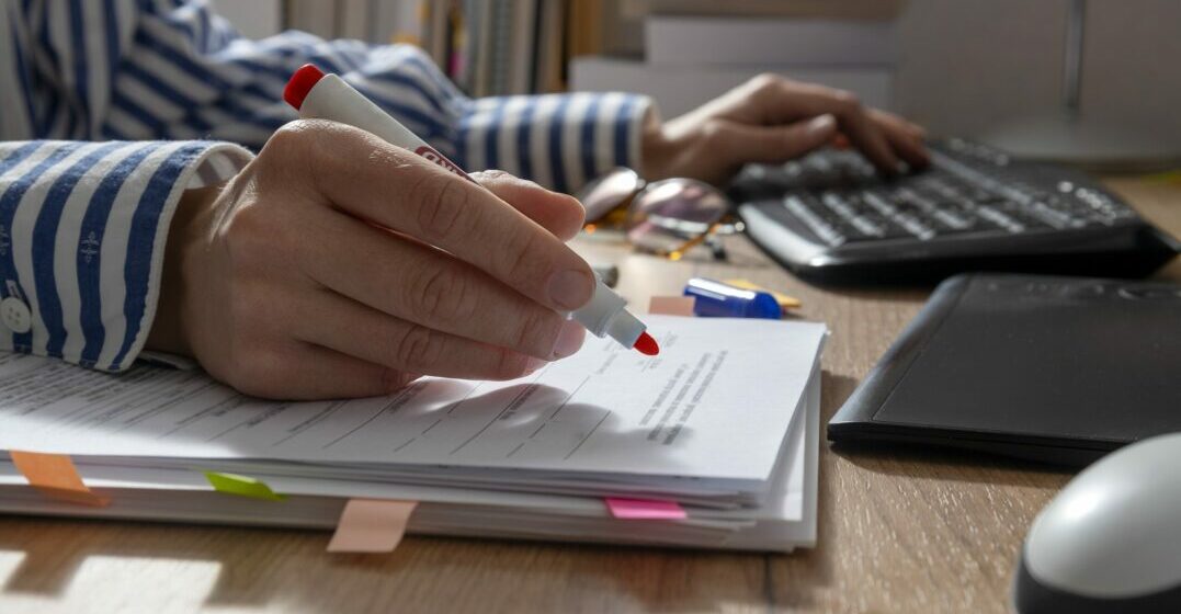 Eine Hand mit Rotstift korrigiert einen Text als deutsche Alternative zu Grammarly
