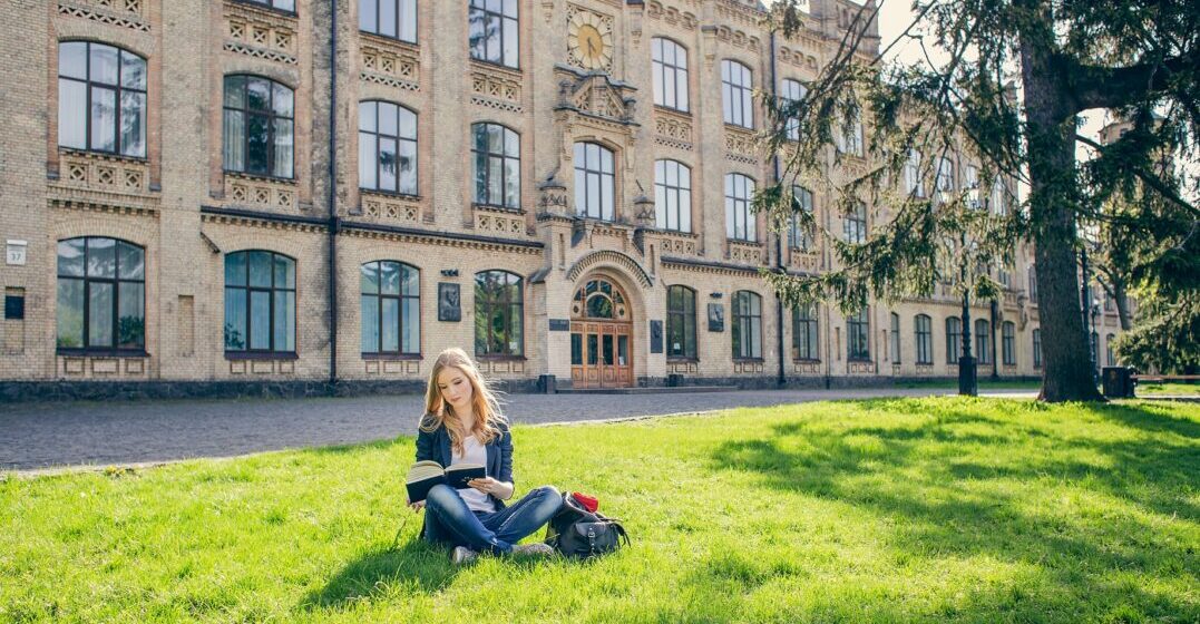 Un estudiante se sienta en el césped frente a una de las mejores universidades de Estados Unidos
