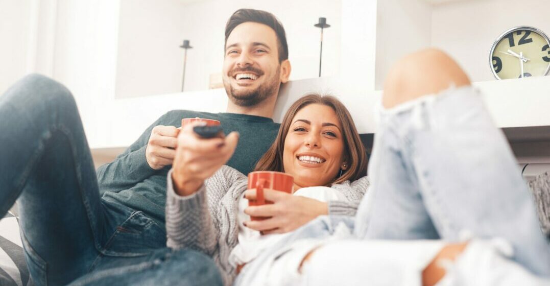 A couple with a remote control watching austrian movies on Netflix