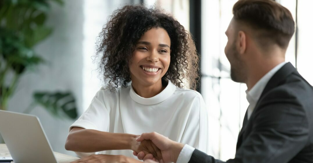A woman and a man shaking hands over a work contract over the average wage in Germany