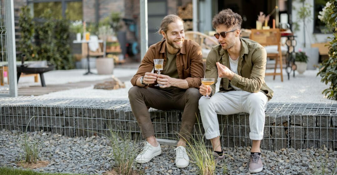 Two male friends sitting on a wall talking about the glottal stop