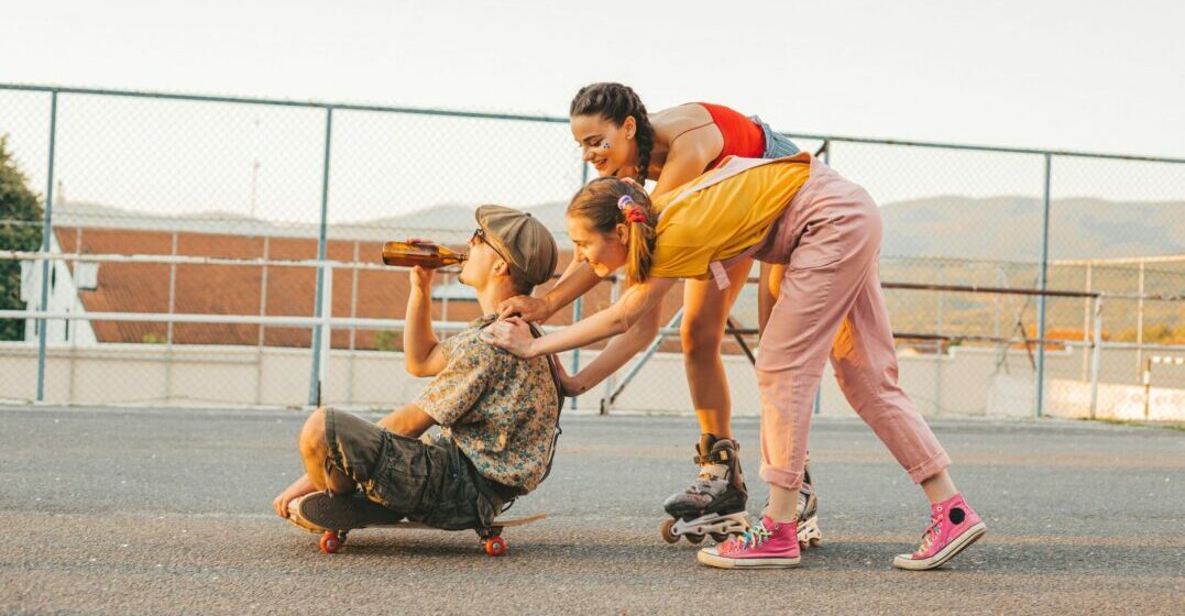 Two girls pushing a guy on a skateboard wearing Berlin fashion styles