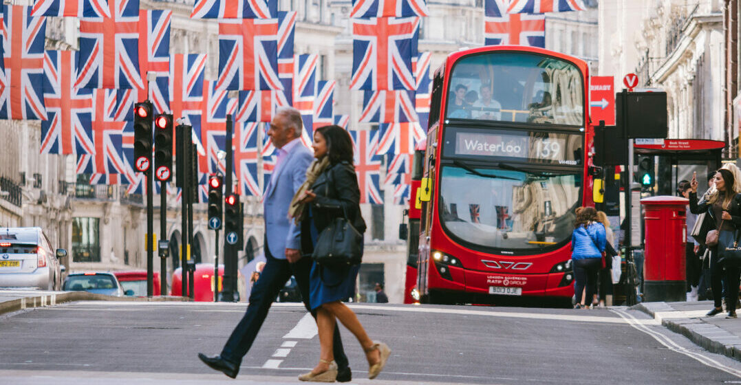 Britain vs. England: Two people crossing a street in London decorated with unions jacks