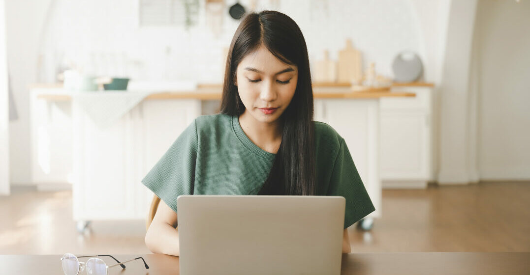 Smiling woman in front of her laütop studying the German alphabet