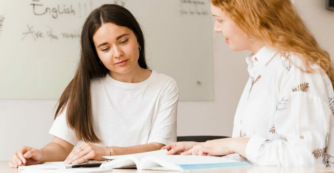 Two young woman looking at a book studying heteronyms
