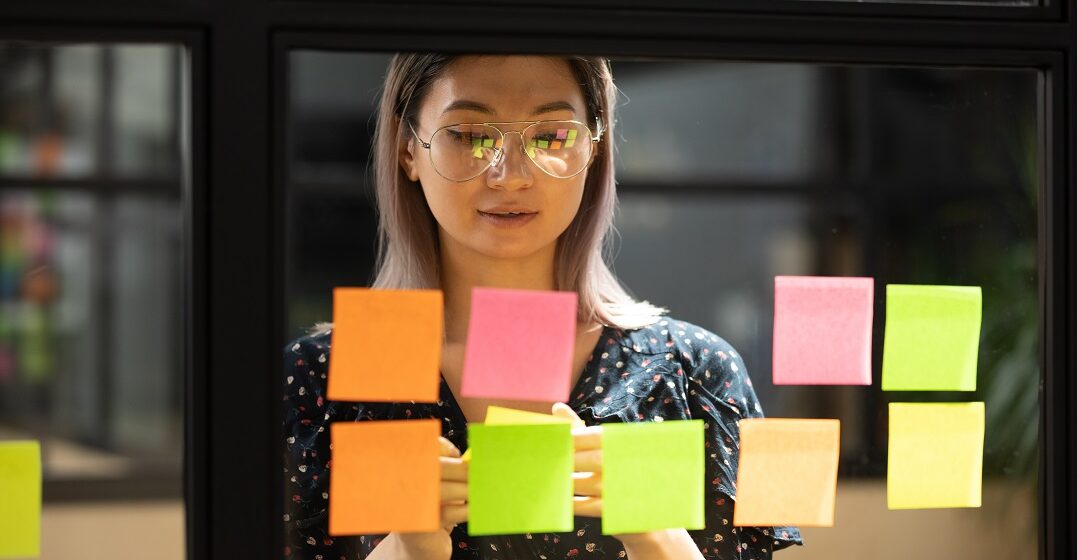 Young woman making a language study plan with sticky notes