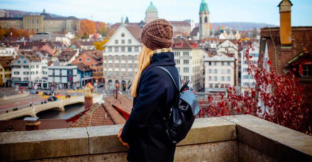 Young woman in front of Zurick skyline wondering how to learn Swiss German
