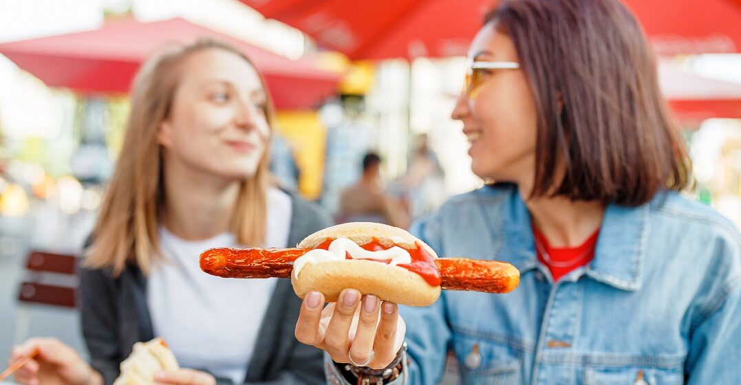 Two female friends eating Bratwurst - traditional German food