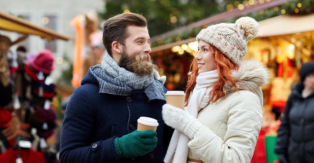 Ein paar auf dem Weihnachtsmarkt tauschen Weihnachtsgrüße auf Englisch aus
